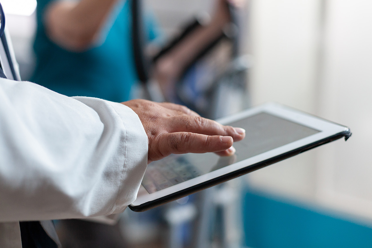 Close up of doctor using digital tablet with touch screen at physical recovery clinic. Medical worker holding modern device and technology to help patient with workout and fitness