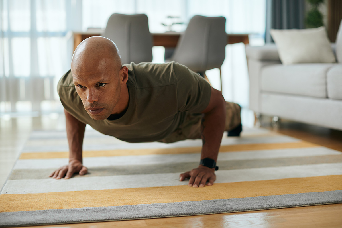 Young black soldier doing push-ups while working out in the living room.
